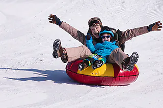Young woman and little boy snowtubing [Microgen (Fotolia.com)]