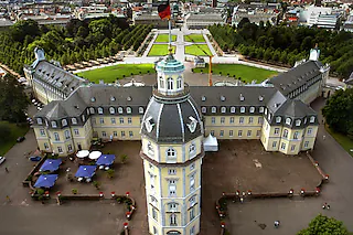 Ein prächtiger Blick ergibt sich am Donnerstag (11.07.2002) auf das Karlsruher Schloss von einem Riesenrad aus, das derzeit hinter dem Schloss aufgebaut ist. Das Karlsruher Schloss wurde 1715 als Residenz des Markgrafen Karl Wilhelm von Baden-Durlach errichtet. Das Schloss, das 1746 ebenso wie die Stadt grundlegend saniert werden musste und bei dieser Gelegenheit vollständig aus Stein gebaut wurde, diente 200 Jahre als Regierungssitz des badischen Herrscherhauses. 1944 wurde es durch Bombenangriffe total zerstört. Nach dem Krieg wurde es wieder aufgebaut und erfreut sich mit den darin integrierten Museen und dem angrenzenden Schlossgarten bei der Bevölkerung und Touristen großer Beliebtheit. dpa/lsw [Foto: Uli_Deck]