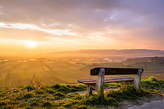 für einen Landschafts-Fotograf ist blauer und wolkenloser Himmel, in etwas genauso langweilig wie ein grauer Wintertag. Daher waren die letzten Tage bzw. Wochen nicht wirklich produktiv. Da heute Morgen, aufgrund der Wetterlage (Wolken über der Rheinebene aber freie Sicht nach Osten), ein schöner Sonnenaufgang zu erwarten war, bin ich kurzerhand um kurz nach 6 aufgestanden und auf den Limberg bei Sasbach gefahren. Von dort hat man einen sehr schönen Blick über den nördlichen Rand des Kaiserstuhls bis hin zum Schwarzwald. Nachdem ich mit der Sonnenaufgang-Ausbeute sehr zufrieden war, bin ich auf dem Heimweg über diese Bank „gestolpert“, von der man einen tollen Blick in den Sonnenaufgang genießen kann. Mit der gerade aufgegangen Sonne im Hintergrund, wer möchte sich dort nicht hinsetzen?  Viele Grüße aus Königschaffhausen André Heid  _________________________ André Heid Im Obstgarten 39 79346 Endingen-Königschaffhausen Handy: 0179/1277408 Telefon: 07642/928747 andre.heid@hotmail.com [Andre Heid]
