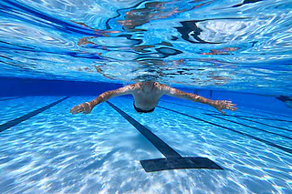 Ein Schwimmer schwimmt durch das Becken im Freibad Hiddesen. In dem Freibad in Detmold wird das Wasser nicht mehr mit Gas geheizt. Die Stadt hatte angekündigt, in allen vier Freibädern vor dem Hintergrund des russischen Angriffskrieges auf die Ukraine, das Wasser nicht mehr zu heizen, um Gas für den Winter einzusparen. (zu dpa-Korr «Frieren gegen Putin? Freibad in Detmold beheizt Wasser nicht mehr») +++ dpa-Bildfunk +++22.07.2022, BZ - FLA: Einige Badbetreiber  senken die Wassertemperatur aufgrund der gestiegenen Energiepreise. Friso Gentsch (dpa) [Friso Gentsch]